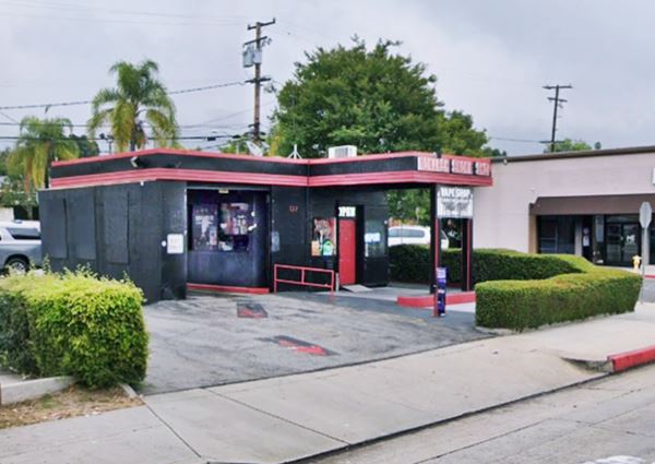 flat canopy, ridged finish, short. Office right, left single bay garage painted black and red, pump islands and slender poles supporting canopy