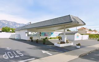 long truncated triangle flat canopy with false mansard roofing on a former gas station, mountains in the distance