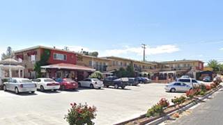  2-story hotel on a corner with cars parked
