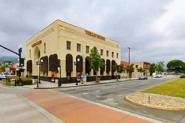 Downtown Azusa Wells Fargo Bank on US66 Block shaped 2 story bank on a corner, with ornamented parapet Art Deco style, WELLS FARGO sign on cornice. Traffic along streets