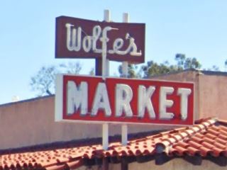 red and white 1950s neon sign atop a red tiled roof WOLFE’s MARKET