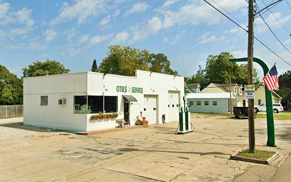 white and green box shaped former gas station CITIES SERVICE with corner office and 2 bays