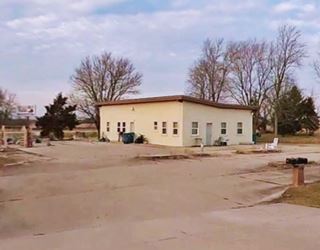 boarded building, box shaped, single story, vacant, parking area around it