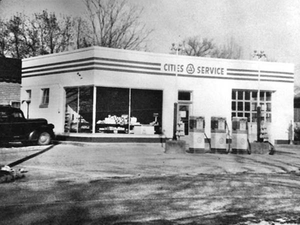 black and white 1940s icebox shaped Cities Service station with 3 pumps with glass corner office