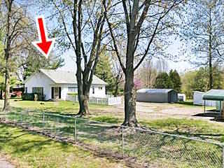 gable roof building with door on corner surrounded by trees seen from US66