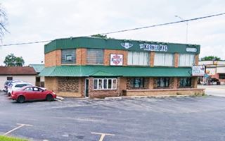 box shaped 2 story brick building, glass brick wall to the left, cars and parking area