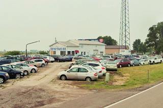 old Benedict gas station US66 in 2023 color, 2023, view of cars parked in auto dealer, seen from US66, Freeway beyond. Gable roof building was the old gas station