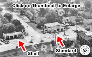 1967 aerial photo Benld black and white aerial photo of two gas station on either side of a street as it meets a highway, trees, cars and houses
