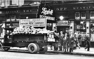 1930s view Berghoff Restaurant black-white, 1930s, people walking. Truck with meat sign reads PRIZE BEEF, in front of Berghoff