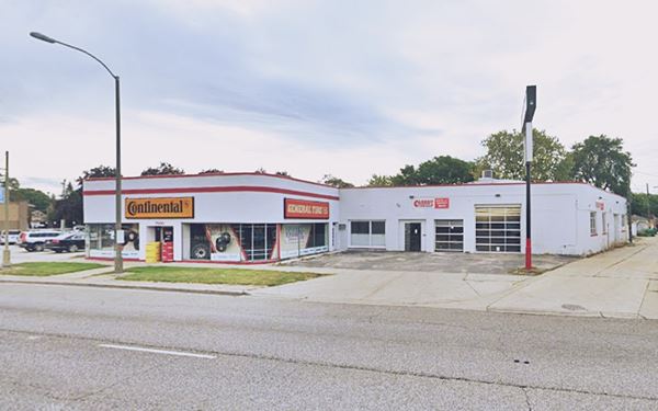 single story former Standard Oil gas station, white, curved office, service bays to right, US66 in front