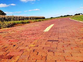 brick roadway Route 66 Auburn IL Brick paved surface with yellow median line, corn field, house in the distance. Route 66, Illinois
