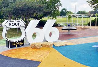 Selfie Stop at Burr Ridge US66 large US 66 Shield with BURR RIDGE written on its base and two sixes, in a playground