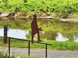 Steel silhouette of an 1850s man. by a canal in a park