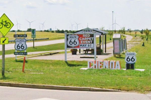Route 66 Chenoa markers and monuments color, signs, shields of US66 and a monument spelling CHENOA with its US66 shield. Fields beyond