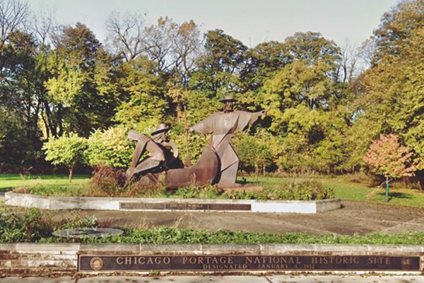park with trees and a bronze statue depicting French explorers