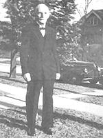 Christian Christensen black and white, c.1945 old man white hair standing on lawn, car behind, pine tree too