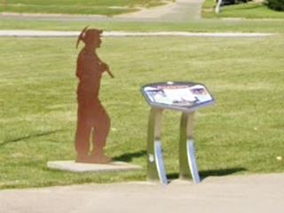 Coal Miner Silhouette in Gillespie steel silhouette of a Coal Miner Silhouette next to a stainless steel lectern-like wayside exhibit on a corner