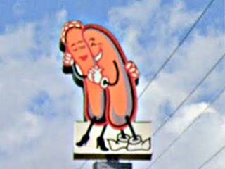 two hugging hot dogs on the top of a neon sign