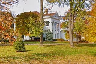 color view of a mansion that is an exact replica of the White House, 2 story, white stone columns in Fall