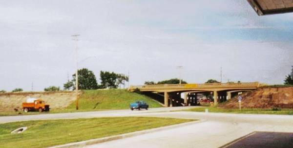 color c.1950s a bridge overpass carries US 66 across a highway, cars, trees and truck