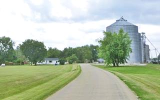 color, highway, fields, trees, buldings and grain elevators to the right