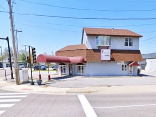 two story shingle gable roof with canopy, a former 1930s gas station on a corner