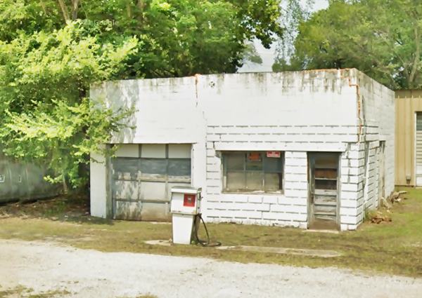 concrete block, single service bay, flat roof gas station with 1970s gas pump