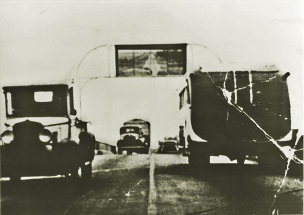 black and white photo c.1940 of vehicles on an overpass with a supported above its central part held by steel arch