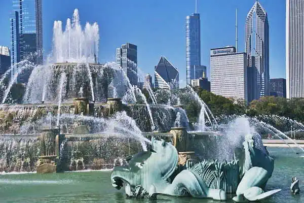 fountain with bronze sea horses, marble and water steams, skyscrapers beyond