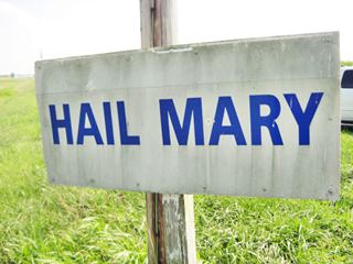 Hail Mary sign White sign with words HAIL MARY written in blue letters. Field behind