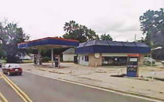 color, box shaped gas station on a corner, canopy to the left, gas pumps, vacant