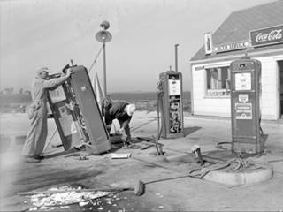 1948 Henderson Standard station Black and white 1948, pumps at Hendersons filling station damaged, two men, gas pumps and building behind