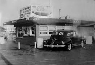 Henry’s hot dog drive in in the 1950s black and white 1950s box shaped hot dog stand, cars around it