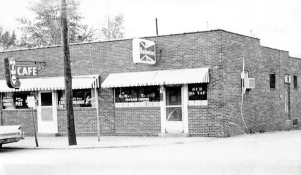 black and white photo 1960s brick building, car and neon sign