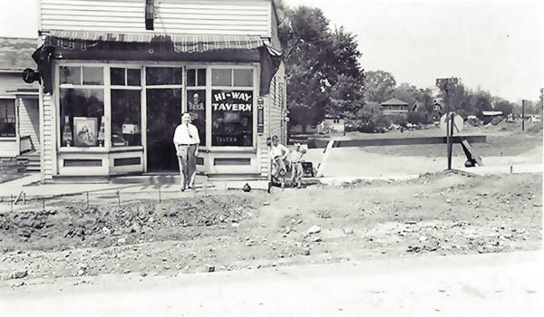 black and white photo 1930s of a man standing in front of a woodframe tavern