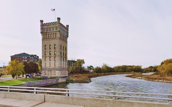 8 story tall tower, with a Middle Ages look, box shaped with corner turrets, river to the right, in fall
