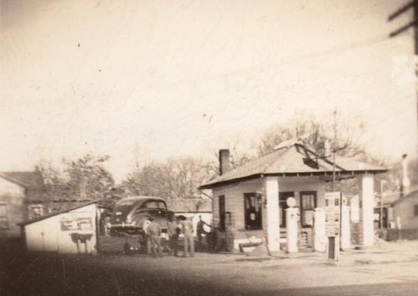 black and white 1948 photo hip rof gas station, men, car on ramp, shed seen from US66