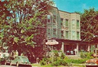 Imperial Hotel 1948, Pontiac 3 story stone corner building, cars parked, trees, people on porch, a hotel. Color, 1948