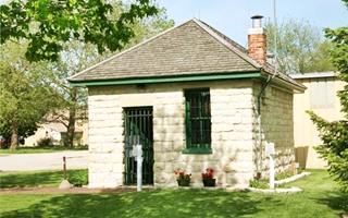 Two-cell Jail, Gardner slate hip roof, stone building in a park, lawn, trees