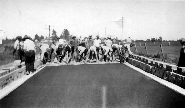 black and white photo of a road building crew laying bricks 1920s on a highway