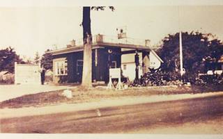 1930s Farr Texaco Lexington IL Black and white, 1930s flat roof and canopy Texaco gas station, man to the left, tree in front, US 66 runs in front of it, 2 gas pumps