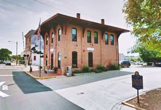 2 story red brick building on a street, an old railroad depot