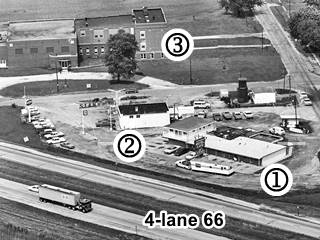 black and white aerial photo, old high school, gas station, and mote with 4-lane divided highway (Route 66) in the foreground