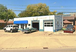 White box-shaped former gas station, 2 service bays, cars parked