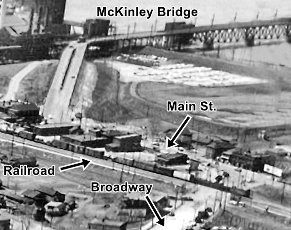 black and white aerial photo from 1960, shows the streets approaching McKinley brige, stores, homes, railroad and the Mississippi river