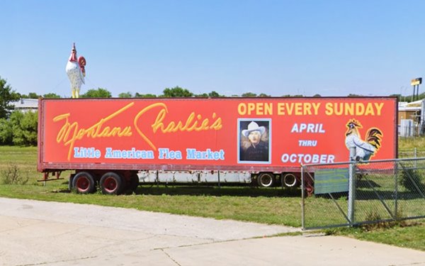 red semi with a large rooster mounted on its roof, photo and autograph of Montana Charleie, and signs indicating flea market open time