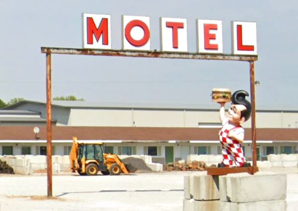 vacant motel in the background, MOTEL sign with red letters on white acrylic squares and a Big Boy restaurant statue on top of a pillar of concrete blocks