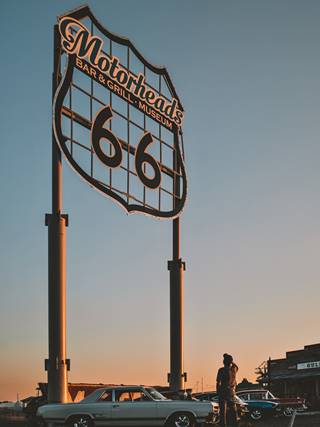 Motorhead's Route 66 sign, Springfield two slender poles hold up a neon sign shaped like a Route 66 shield at Motorhead. Color, evening