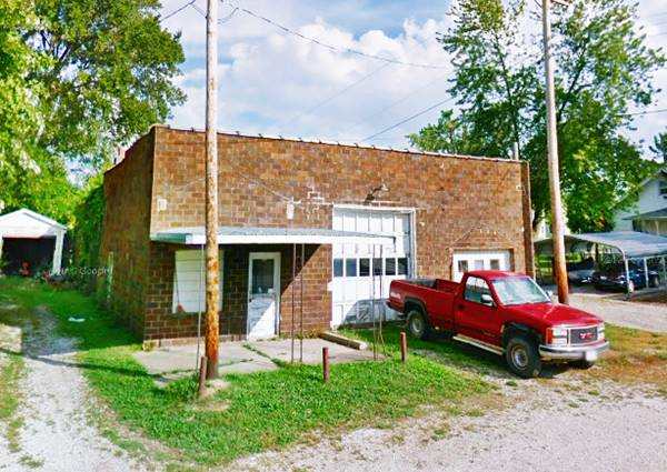 Old garage on Route 66 in Mt. Olive single story flat roof brick building with two service bays and corner office with pick up parked on the white gravel driveway