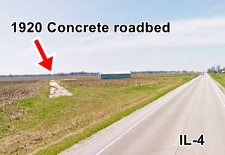 narrow strip of cracked concrete with weeds in a plowed field